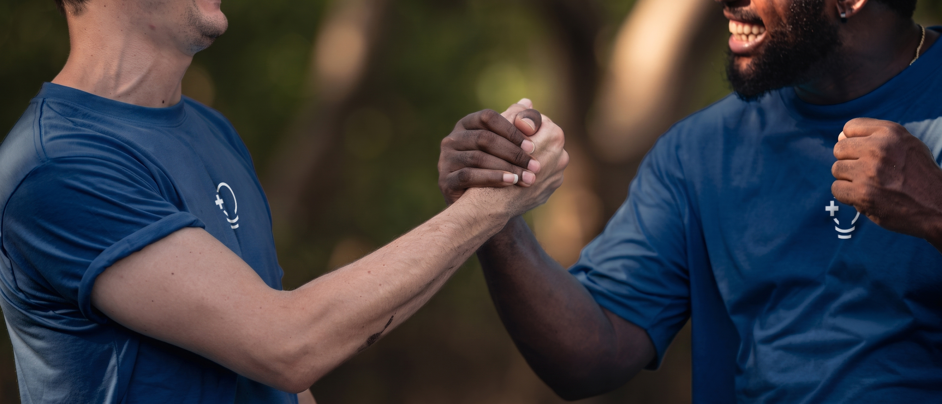 Two volunteers in IdeaCrew shirts clasping hands outdoors