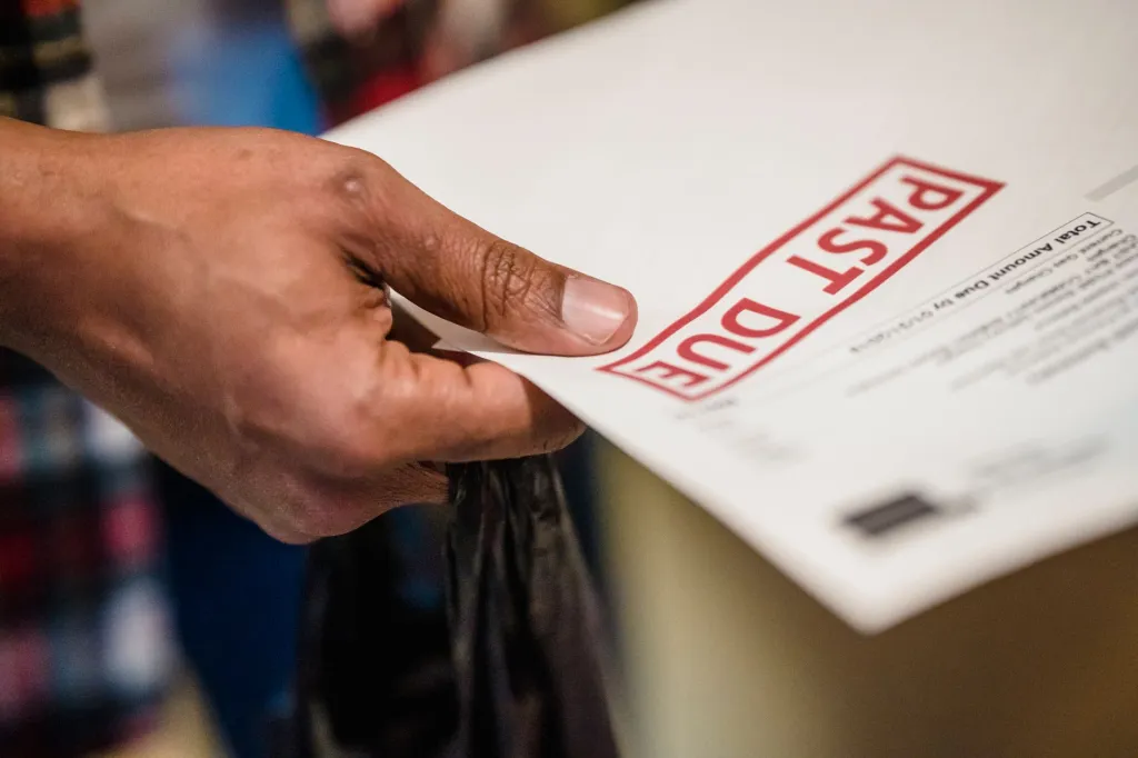 A hand holding a past-due medical notice